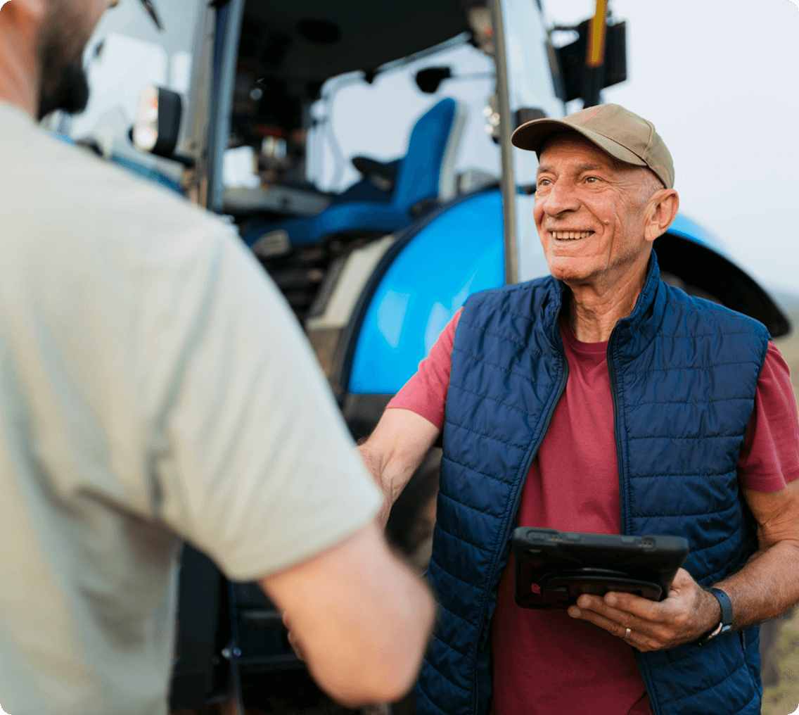 Farmer shaking hands near tractor