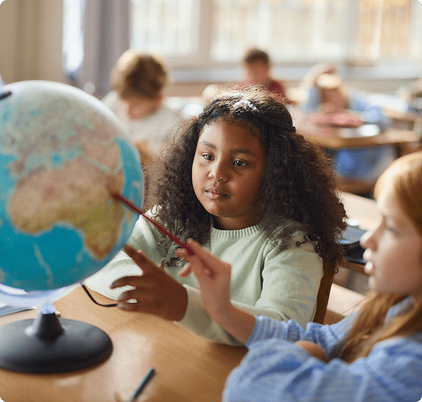 Children exploring a globe in classroom
