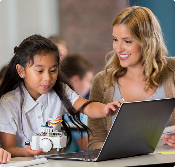 Girl holds robot near computer