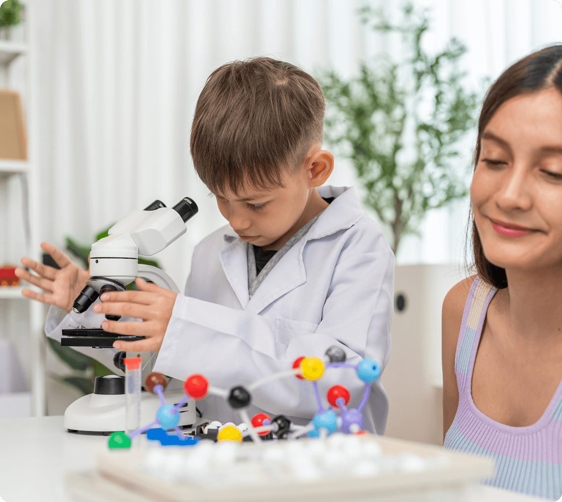 Child examining microscope in lab coat