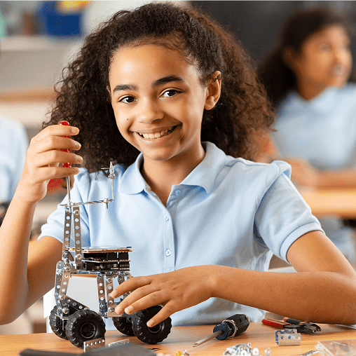 Young girl assembling a small robot in a classroom.
