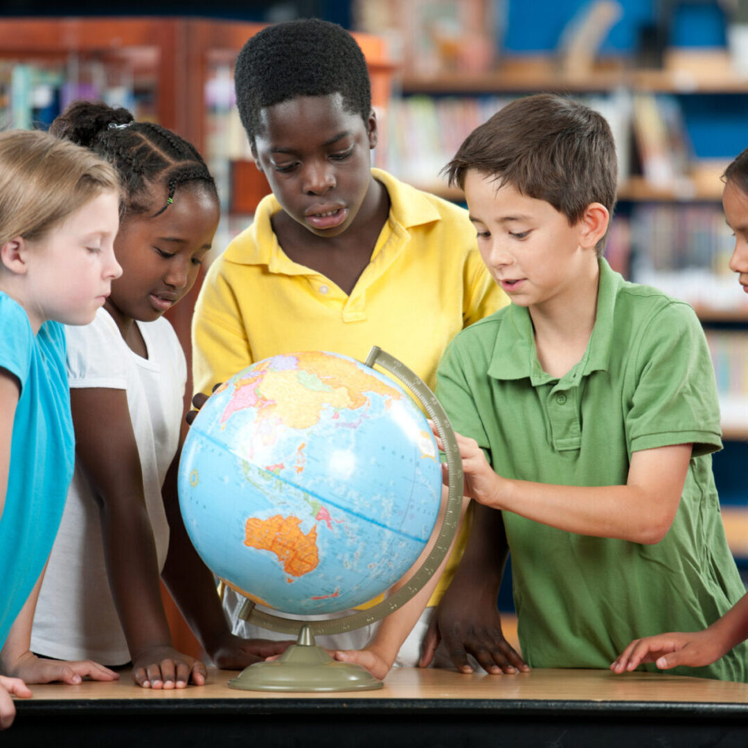 Children gathered around a globe in a classroom setting.