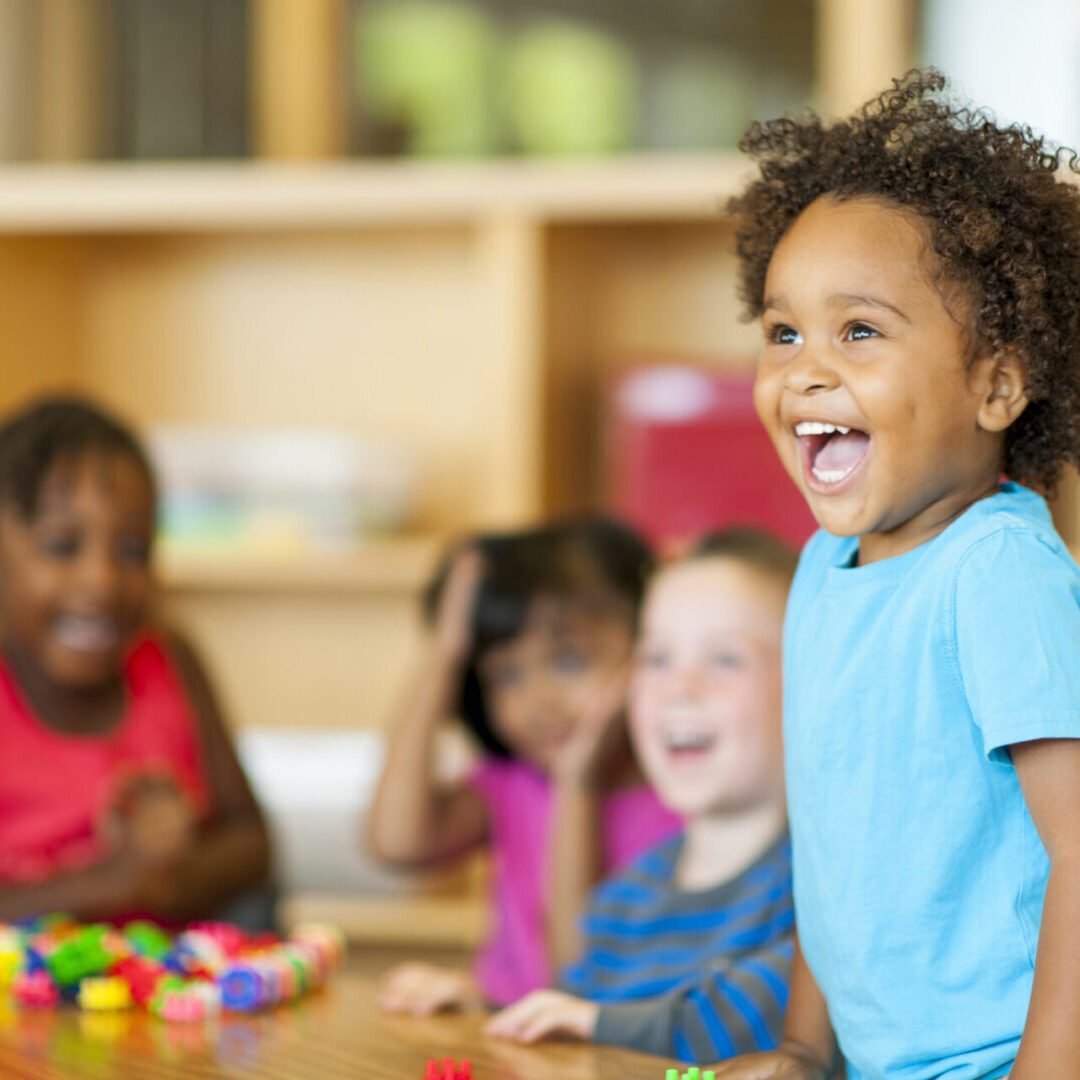 Happy children playing and laughing in a classroom setting.